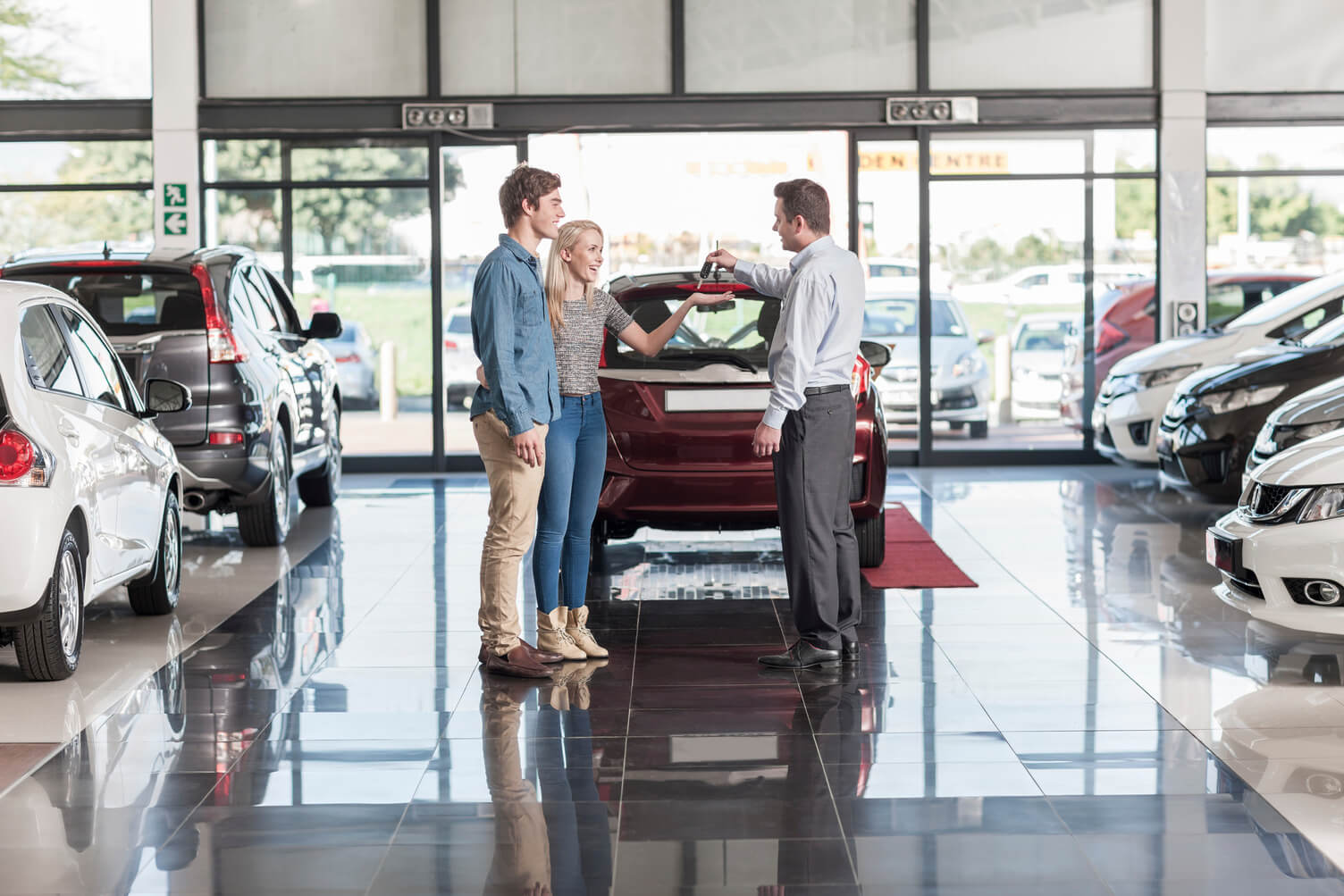 Man buying a car from a woman in a dealership