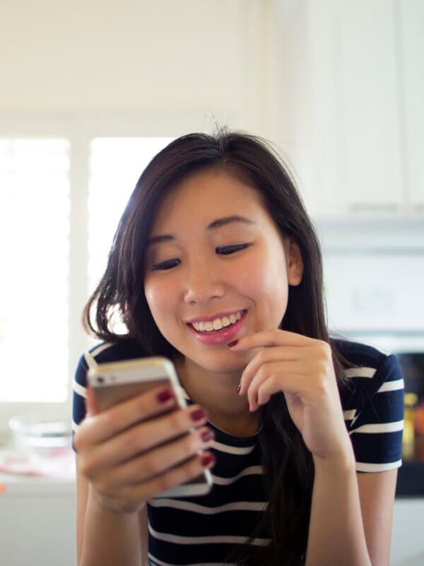 Woman smiling while reading her phone