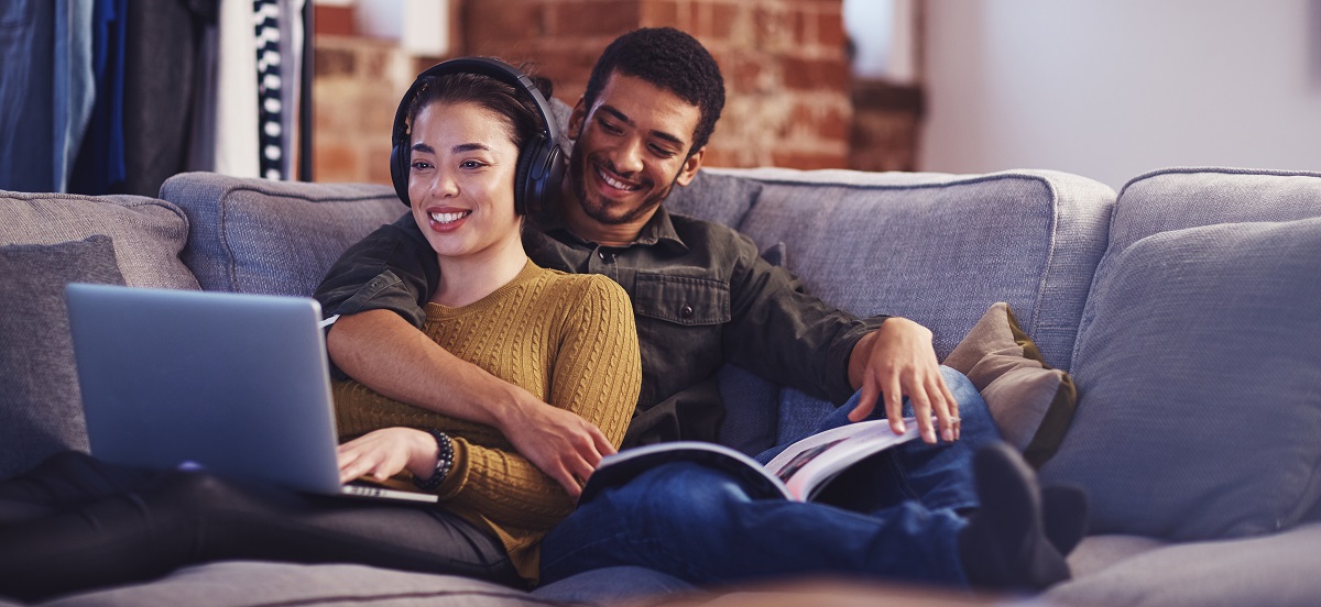 Man and woman sat together on a sofa looking at a laptop