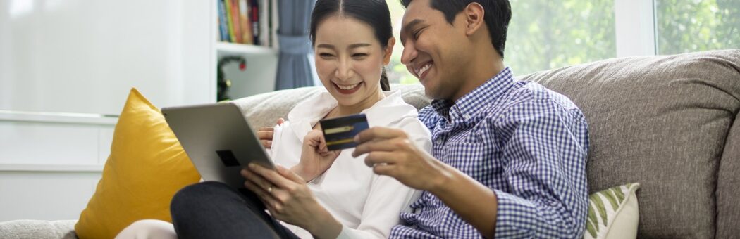 Happy couple shopping online with holding credit card and laptop and sitting at home together, lifestyle concept.