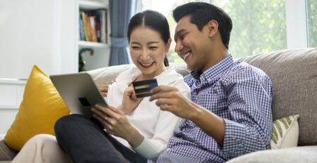 Happy couple shopping online with holding credit card and laptop and sitting at home together, lifestyle concept.