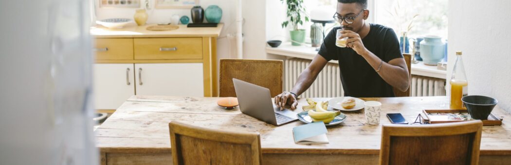 Man sat at dining table with laptop