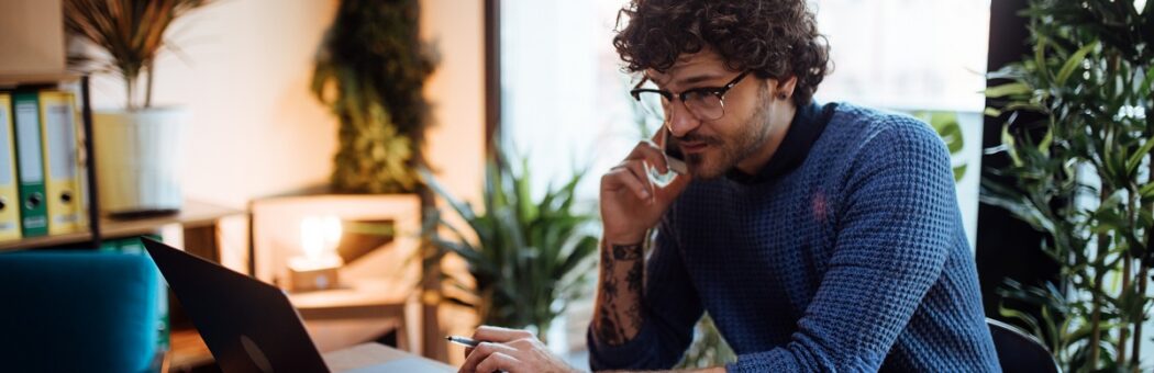 Man on the phone while browsing on a laptop