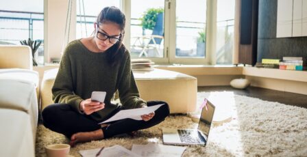 Young woman sitting on the floor of her living room and working