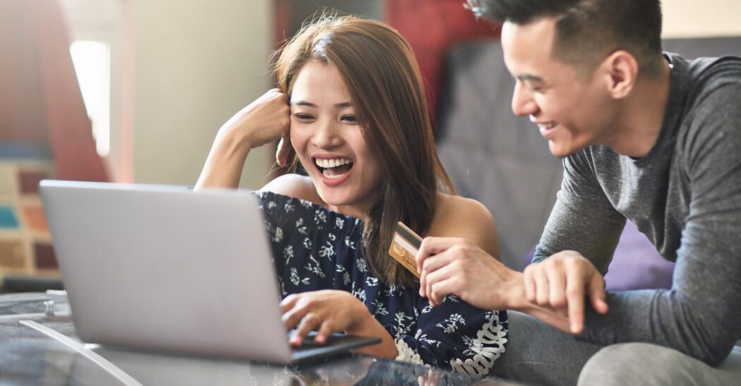 Happy couple shopping online on laptop