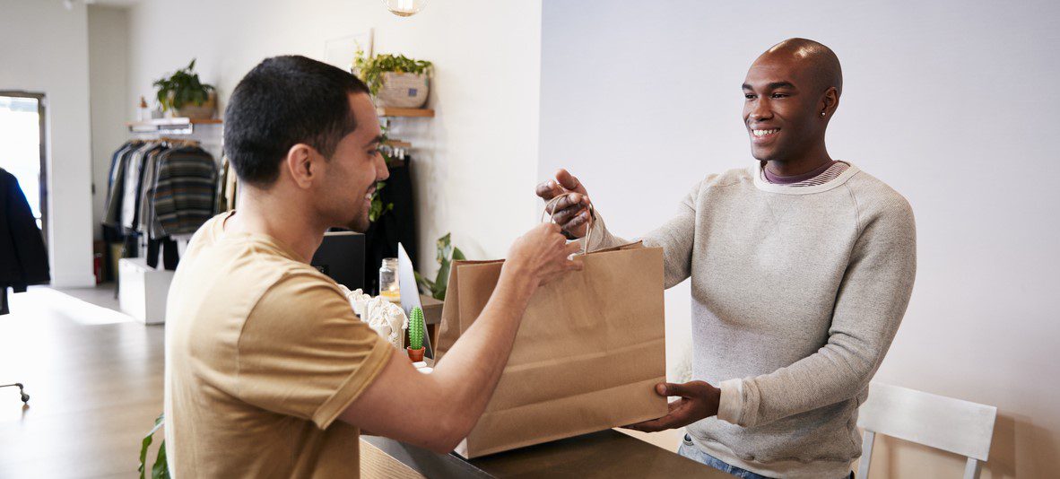 Man smiling to checkout assistant while buying an item in a shop