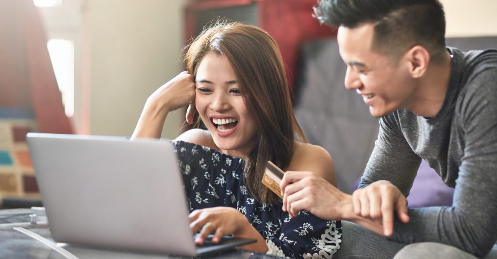 Happy couple shopping through laptop at home