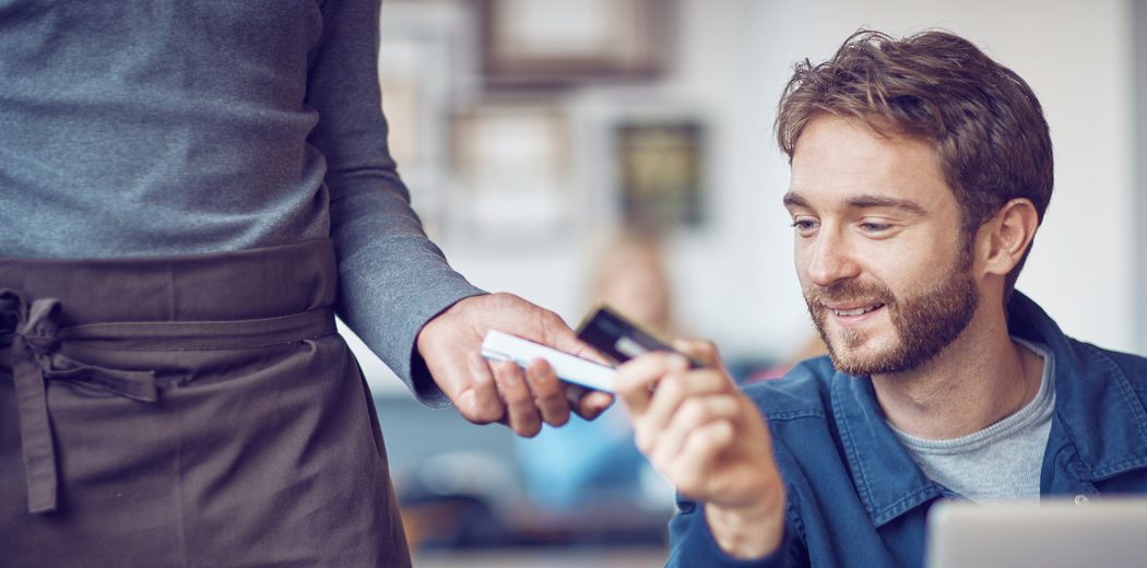 Man sitting at table paying for coffee