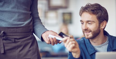 Man sitting at table paying for coffee