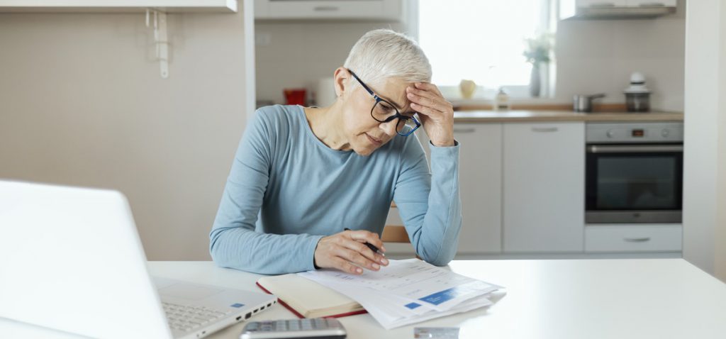 Older woman sitting in kitchen looking at paperwork