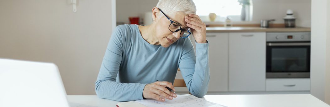 Older woman sitting in kitchen looking at paperwork