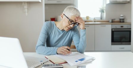 Older woman sitting in kitchen looking at paperwork