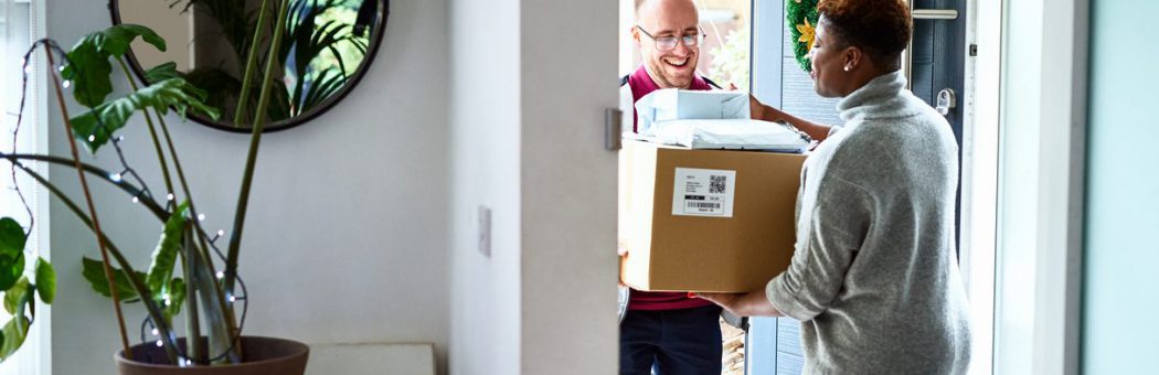 Delivery man handing over cardboard box to female customer