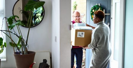 Delivery man handing over cardboard box to female customer