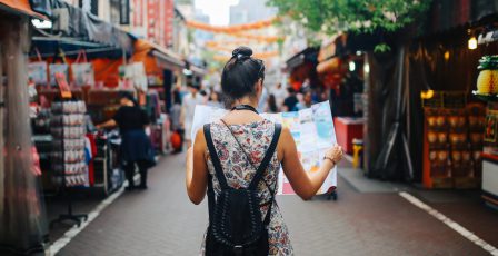 young solo traveler woman in Singapore street market checking the map