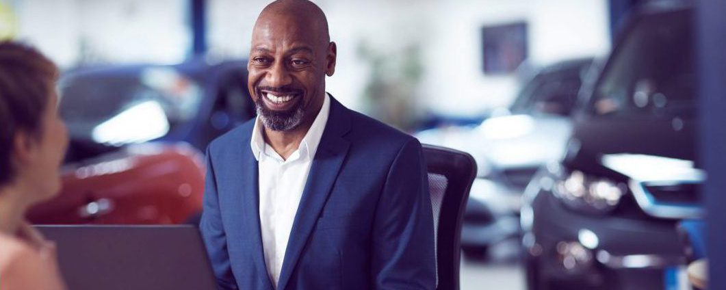 Car dealer talking to a customer with cars in the background