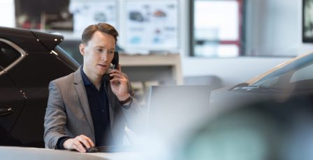 Car salesperson talking on landline phone