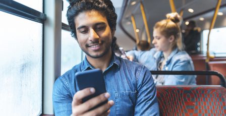 Man smiling while engaging with his phone in the bus