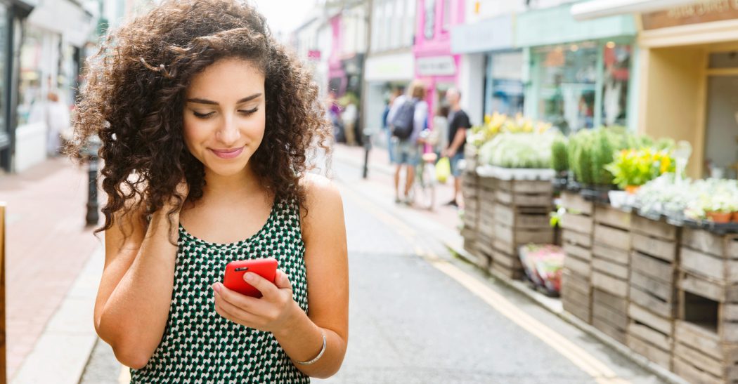 Young woman using smart phone on street