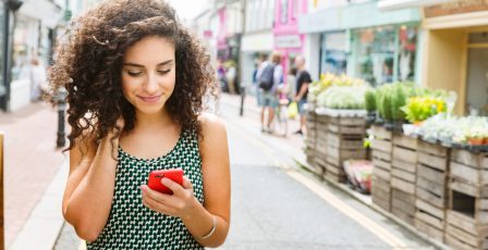 Young woman using smart phone on street