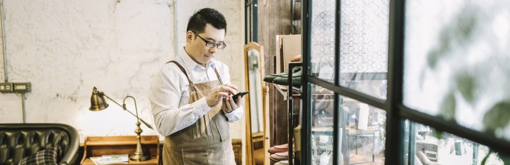 Small business owner sending voice message while standing by window.