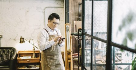 Small business owner sending voice message while standing by window.