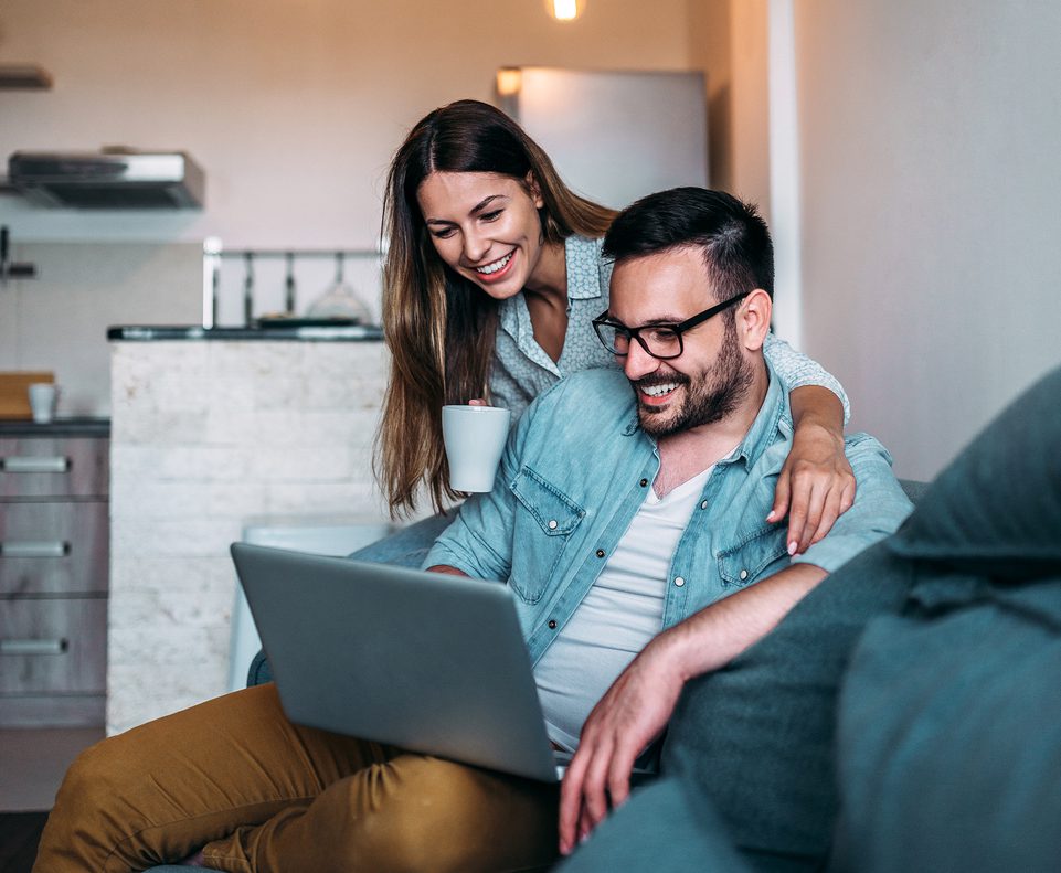 Couple using laptop while sitting on the sofa