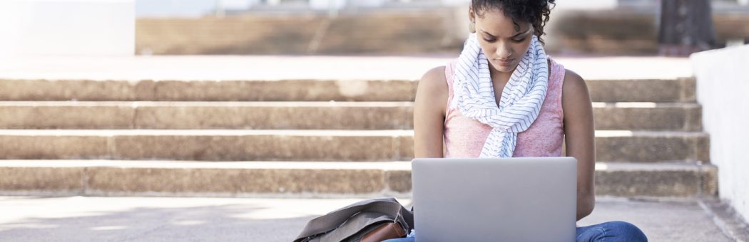 Young woman sitting outside using a laptop