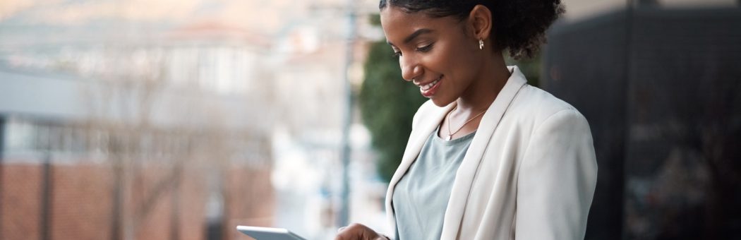 Young businesswoman using a digital tablet out on the balcony of a modern office