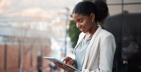 Young businesswoman using a digital tablet out on the balcony of a modern office