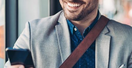 Man smiling while using his phone on a bus