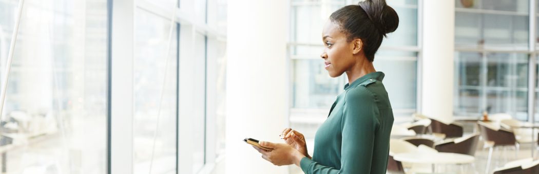Businesswoman at window while holding their phone