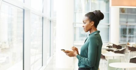 Businesswoman at window while holding their phone