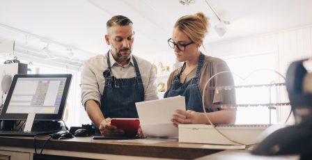 Serious owners discussing over financial receipt at checkout counter in store