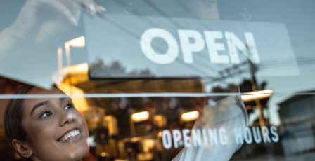 Woman wearing an apron opening up a shop