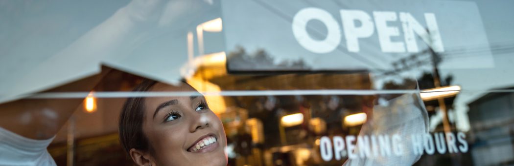 Woman wearing an apron opening up a shop