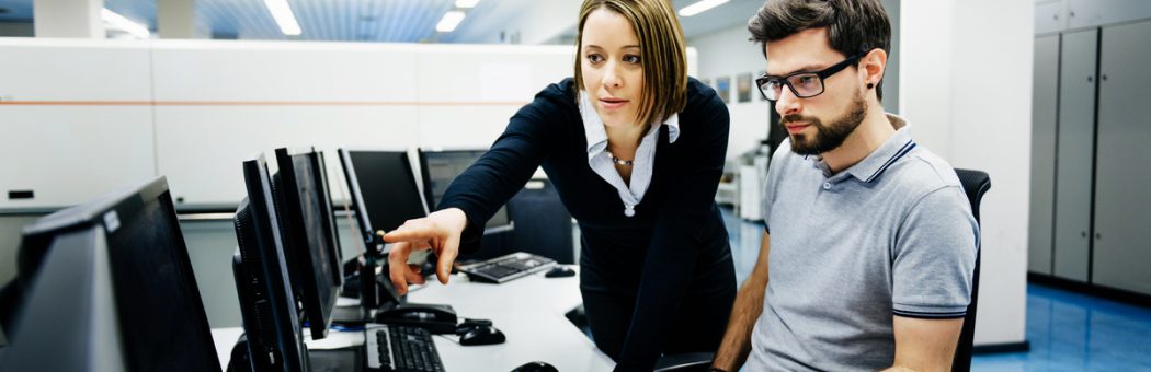 Two professionals looking at data on a computer