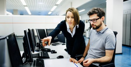 Two professionals looking at data on a computer