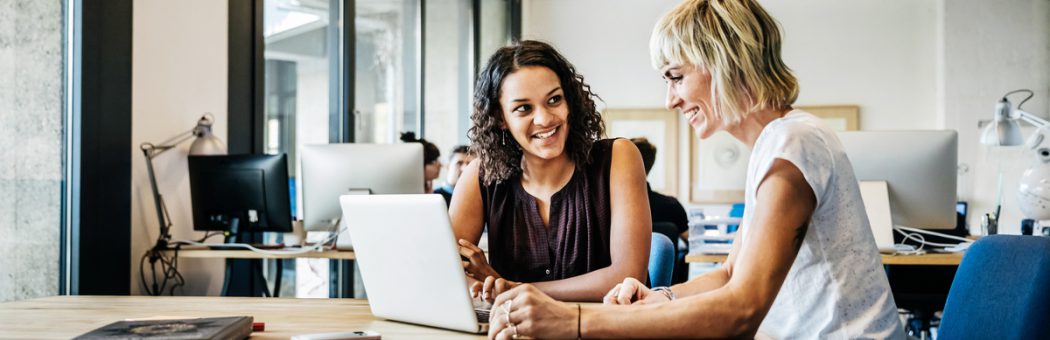 Two businesswomen talking in a meeting with laptop