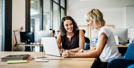 Two businesswomen talking in a meeting with laptop