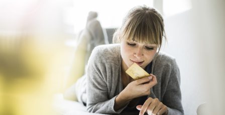 Woman lying on couch with credit card and tablet