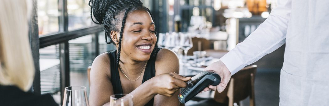 Young woman using a credit to pay for a bar bill