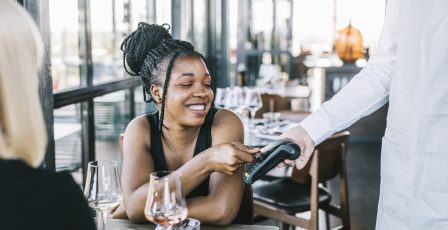 Young woman using a credit to pay for a bar bill