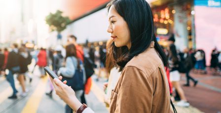 Young woman in a metropolitan city looking at her phone