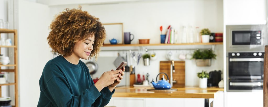 Woman using smartphone in kitchen