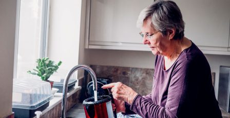 Elderly woman filling up a kettle