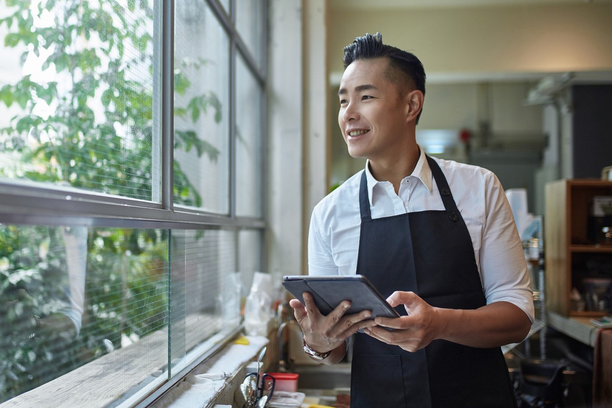 Barista with a tablet while looking through cafe window