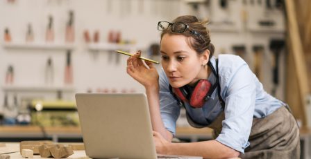 Small business owner using laptop in workshop