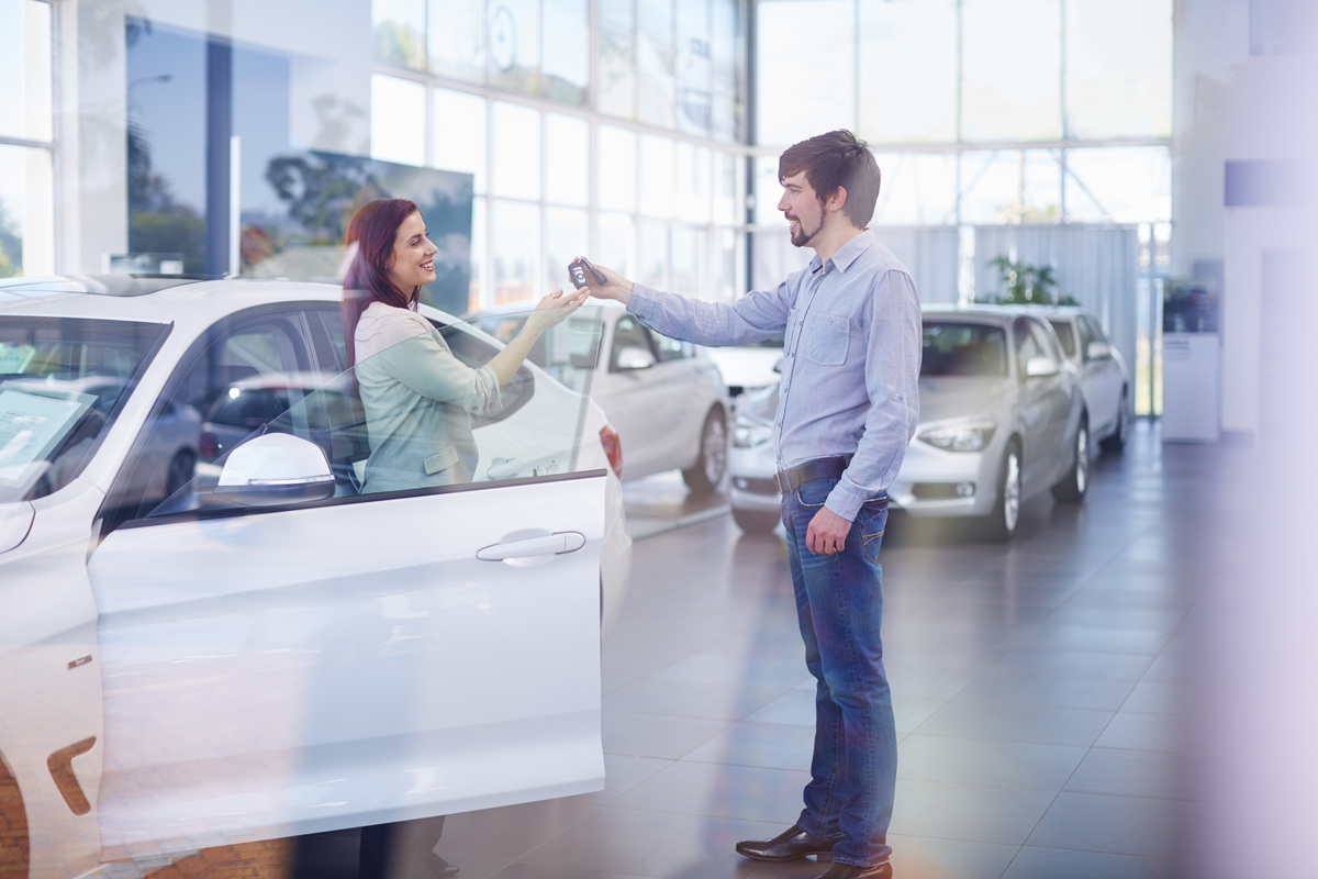 Car dealer giving key to client