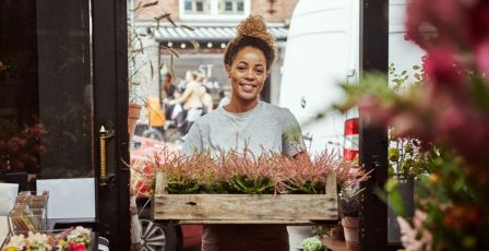 Florist standing holding a crate of flowers